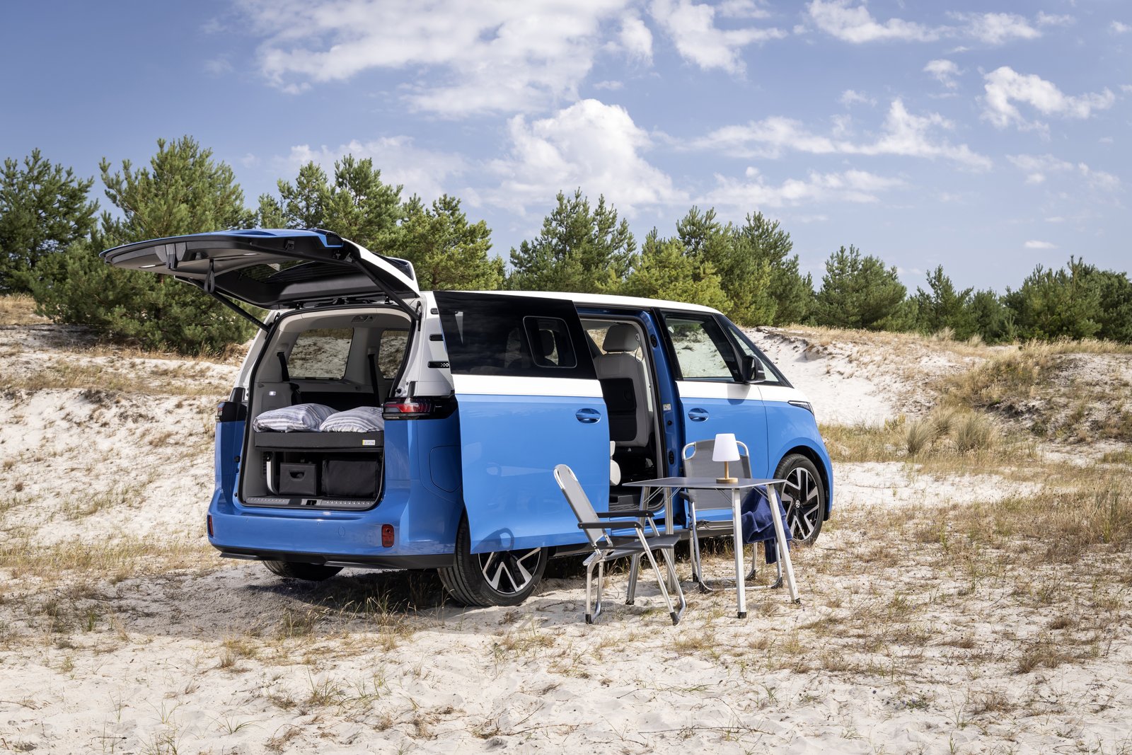 Mesa de camping desplegada junto a la puerta lateral de la Volkswagen ID. California Cruise