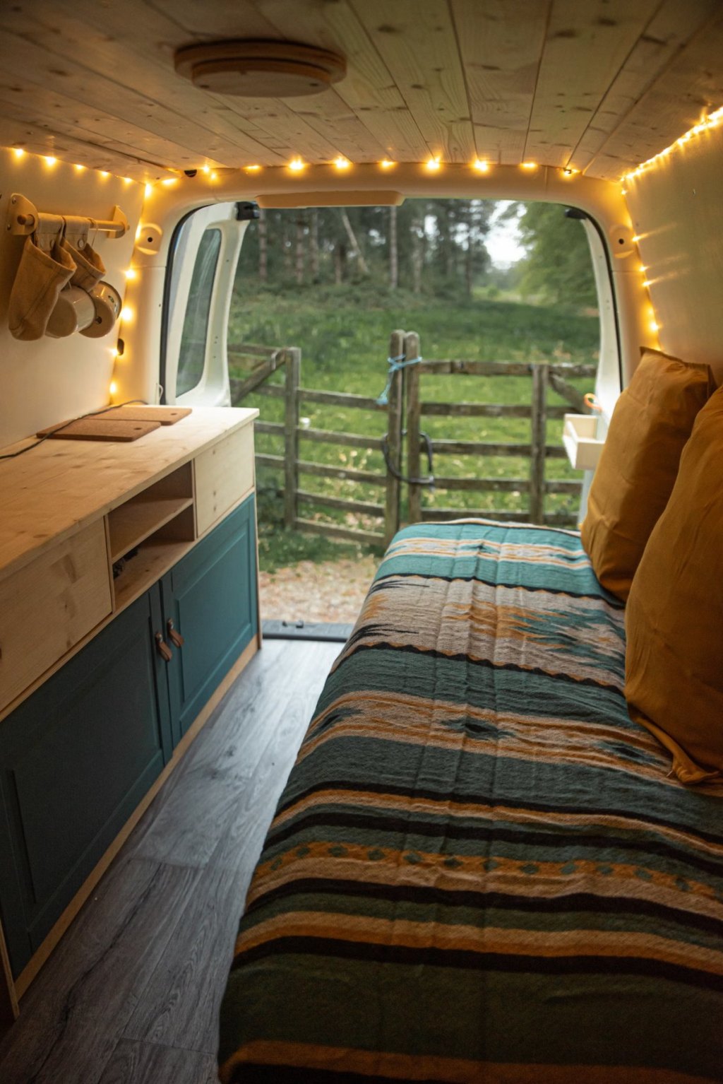 Interior de una furgoneta camper camperizada con muebles de madera y cama