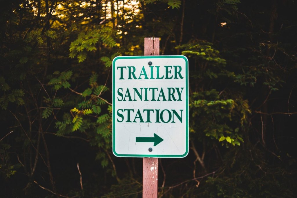 Cartel indicador de un punto de vaciado de aguas residuales para caravanas y autocaravanas junto a un bosque