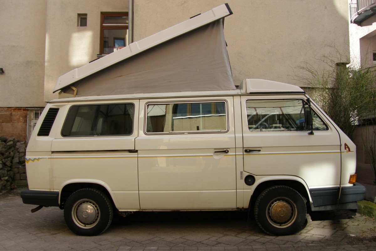 Volkswagen California de 1990 aparcada con el techo elevable abierto, vista lateral